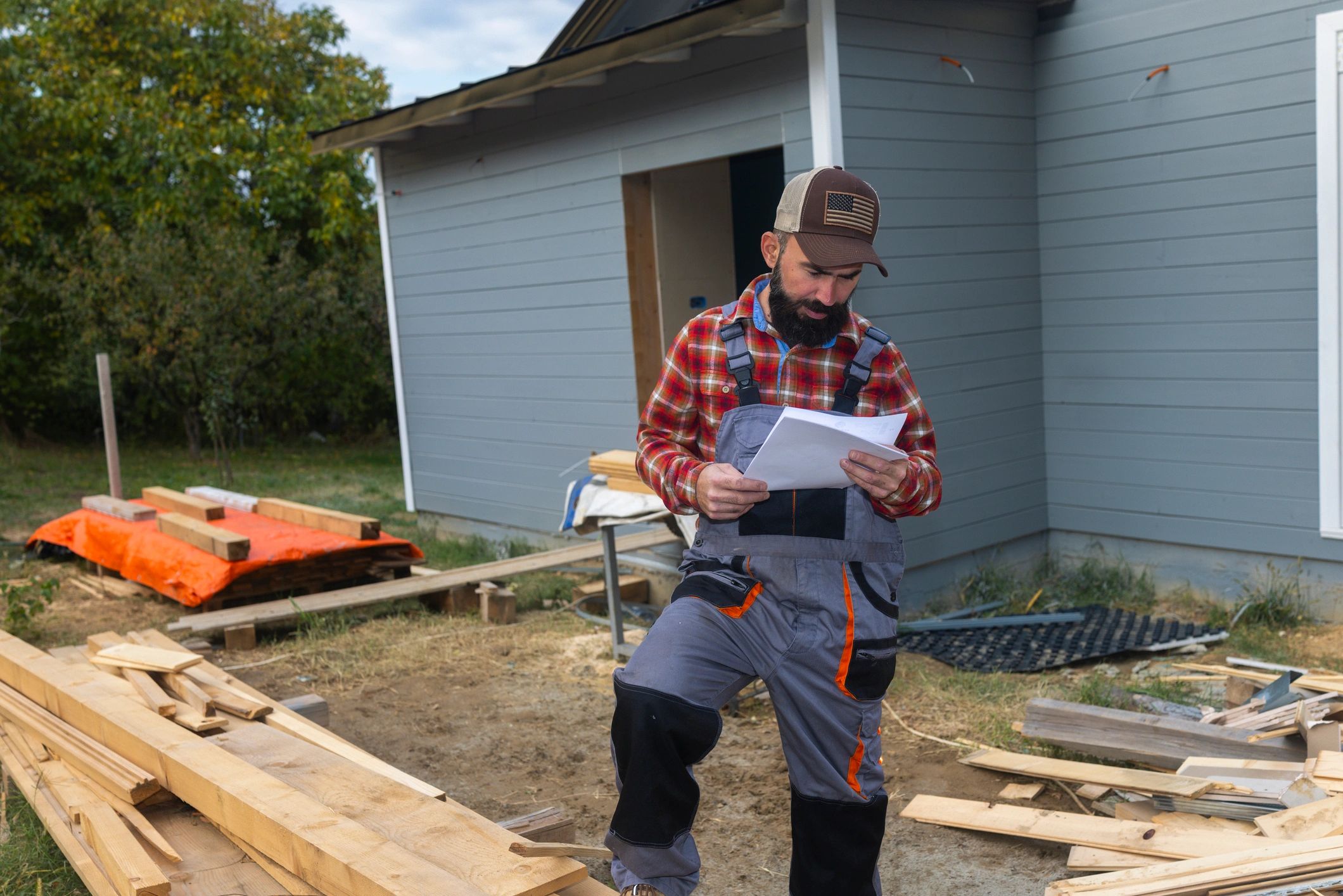 Construction worker reviewing plans at a framed building site